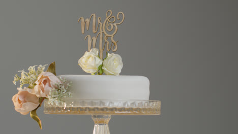 Close-Up-Of-Wedding-Cake-On-Stand-Against-Grey-Studio-Background-At-Wedding-Reception-1